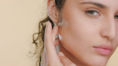 Latina with natural curls strokes jawline, fresh balanced skin