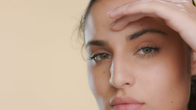 Fair-skinned Latina with green eyes strokes forehead