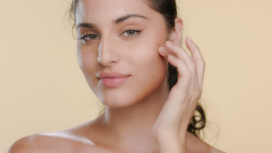 Curly-haired young Latina touches cheek illustrates elastic skin