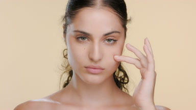 Hispanic beauty model strokes under eye area, elastic skin