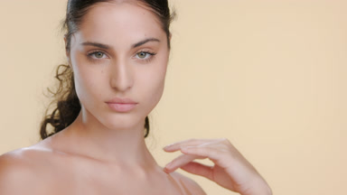 Young fair-skinned woman with curls strokes clavicles