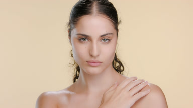 Young Latin beauty poses hand on shoulder, nourished skin