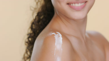 Young Latin model with light skin applies body cream on shoulder