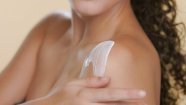 Latin model with light skin applies body lotion on her shoulder