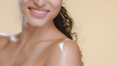 Fair Latin model smears body cream on shoulder, balanced skin