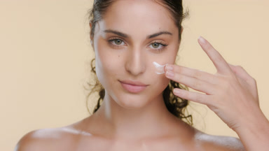 Spanish woman smears cream on cheek, revitalized skin