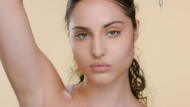 Young Latina applies serum under eye, hand overhead