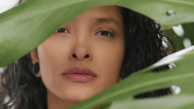 Young argentinean beauty gently strokes her cheek among leaves