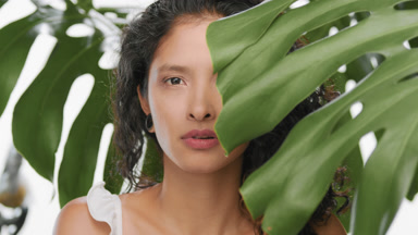 Skincare model opening eyes and looks at the camera in plants