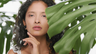 Cosmetic model strokes her cheek with a finger of her hand
