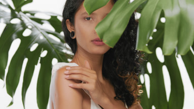 Argentinean woman surrounded by leaves strokes her shoulder