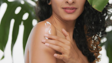 Argentinean skincare model applies body cream on her shoulder