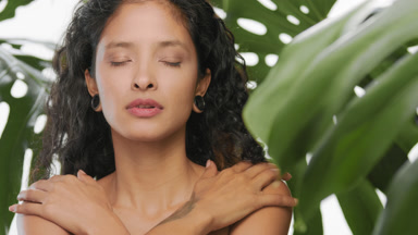 Latin beauty stroking both her shoulders with pleasure in leaves