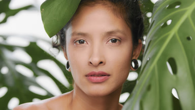 Commercial beauty model surrounded by plants looking at camera