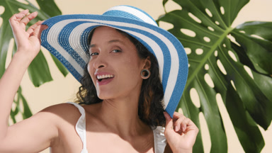 Positive argentinean model playfully putting a sun hat on