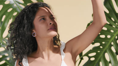 Young woman shielding her face from the sun with hand