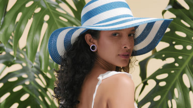 Beauty model in white-blue striped sun hat looks over shoulder