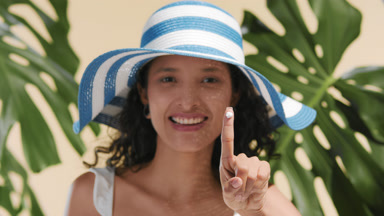 Bikini-style woman demonstrating sun cream drop on her finger