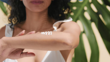 Confident argentinean model applying sunscreen cream on forearm